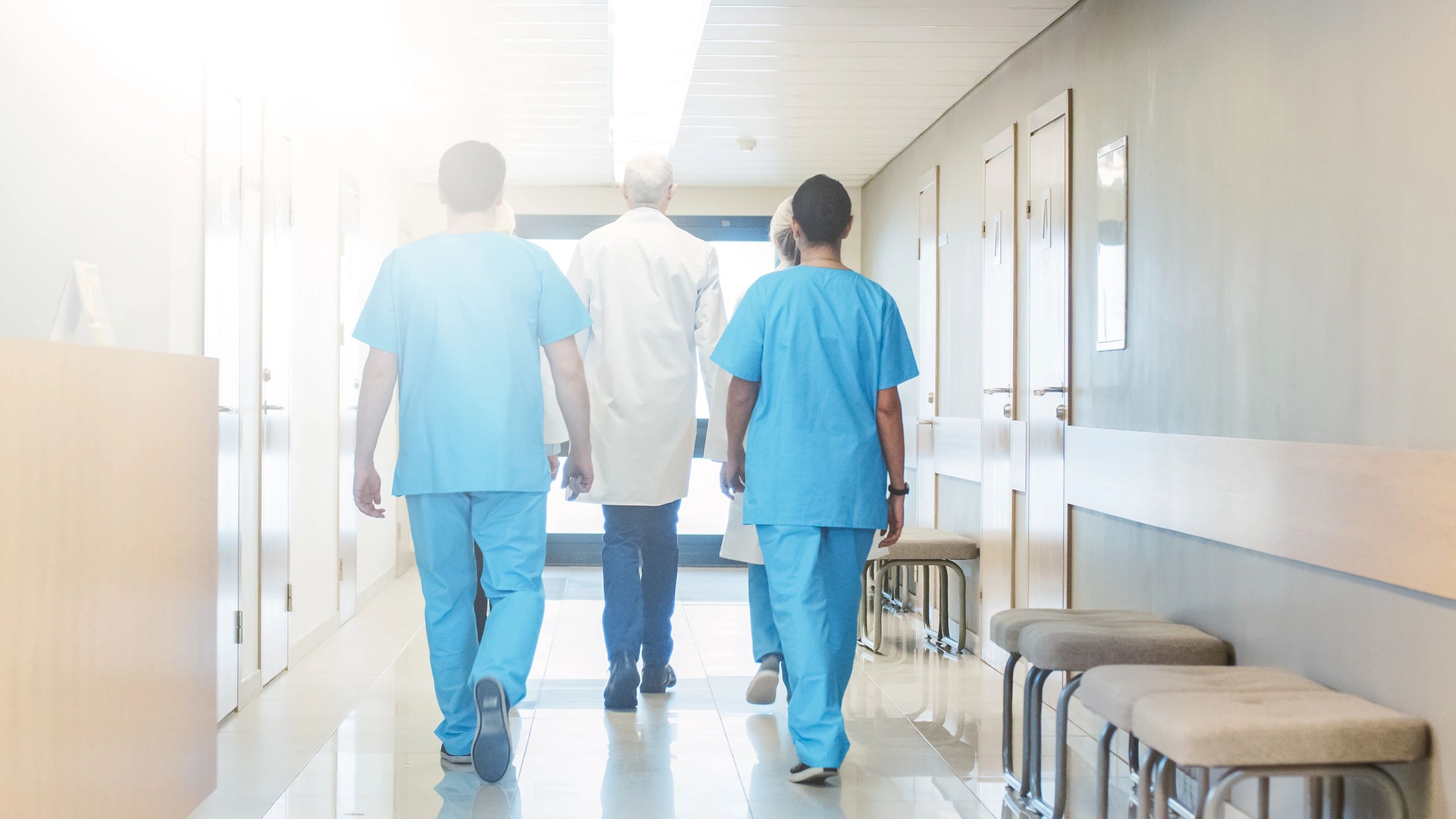 Three healthcare professionals walking down hospital corridor
